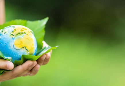 Little girl holding small planet in hands against spring or summer green background. Horizontal banner for web design with copy space.Ecology, environment and Earth day concept. Child holding small planet in hands against spring or summer green background. Horizontal banner for web design with copy space.Ecology, environment and Earth day concept.